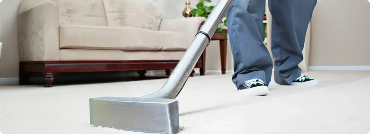 Carpet cleaning technician using a hot-water extraction wand on a light-colored carpet in a living room, Omaha, NE.